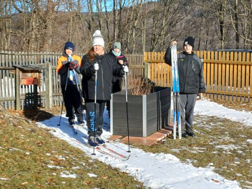 Fünf Personen stehen mit Skiern in einem verschneiten Garten.