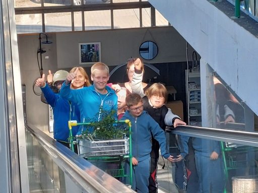 Eine Gruppe von Kindern fährt mit einem Einkaufswagen auf einer Rolltreppe.