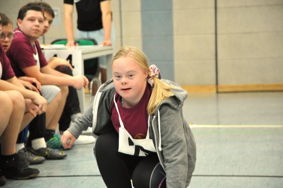 Ein Mädchen mit Down-Syndrom in sportlicher Haltung während eines Wettkampfs.