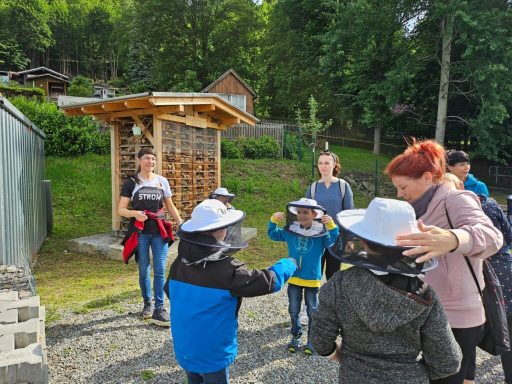 Gruppe von Kindern und Erwachsenen mit Schutzhelmen in einer Naturumgebung.