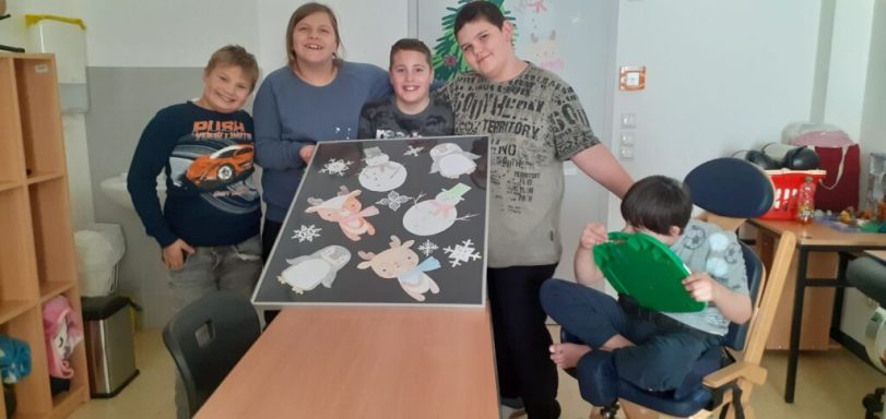 Fünf Kinder in einem Klassenzimmer zeigen stolz ihr Kunstprojekt.