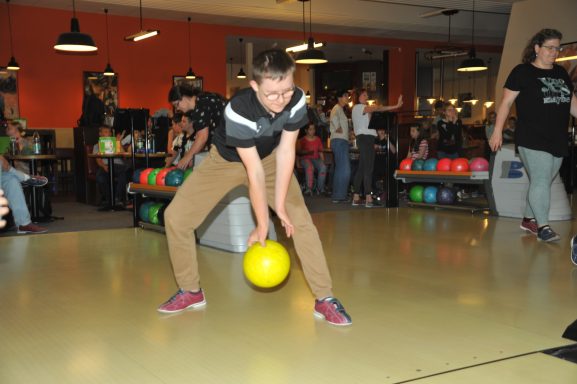 Junger Mann bereitet sich darauf vor, eine gelbe Bowlingkugel zu werfen.