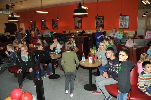 Gruppe von Kindern und Jugendlichen in einem lebhaften Café mit roten Wänden.