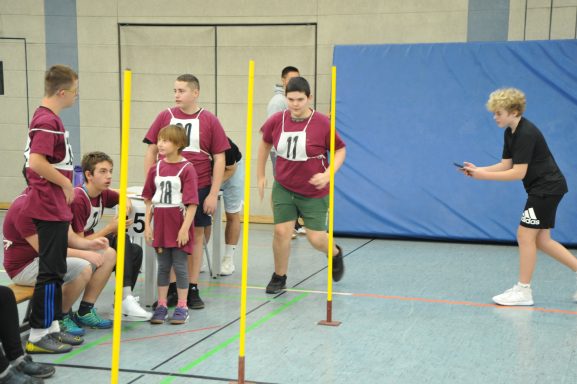 Junge Sportler absolvieren einen Staffellauf in einer Turnhalle mit Markierungen.