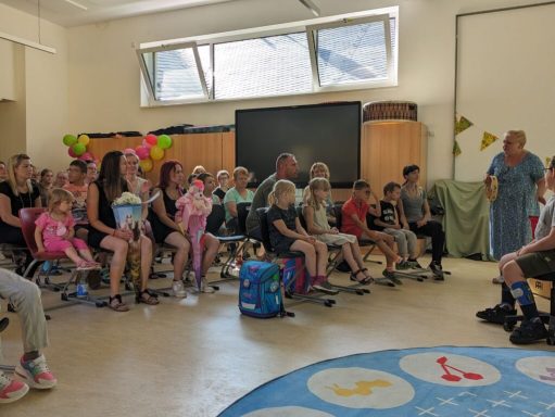 Gruppen von Kindern und Erwachsenen sitzen im Raum, um eine Aufführung zu sehen.