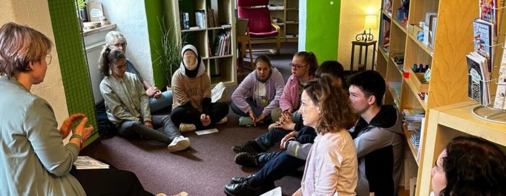 Gruppendiskussion in einem Bücherraum mit mehreren Personen, die aufmerksam zuhören.