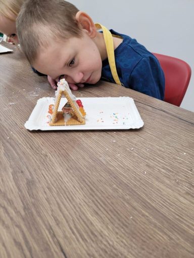 Ein Junge ruht seinen Kopf auf dem Tisch neben einem kleinen essbaren Bauwerk.