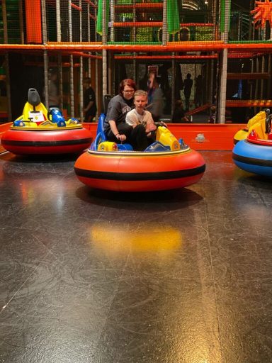 Familie fährt gemeinsam auf einer Fahrt in einem Spielzeug-Auto im Innenbereich.