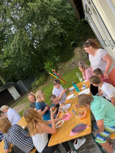 Menschen sitzen an einem Tisch im Freien und genießen gemeinsam Essen und Spiele.