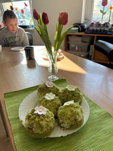 Grüne Kuchen mit Blumen dekoriert, im Vordergrund, mit Tulpen im Hintergrund.