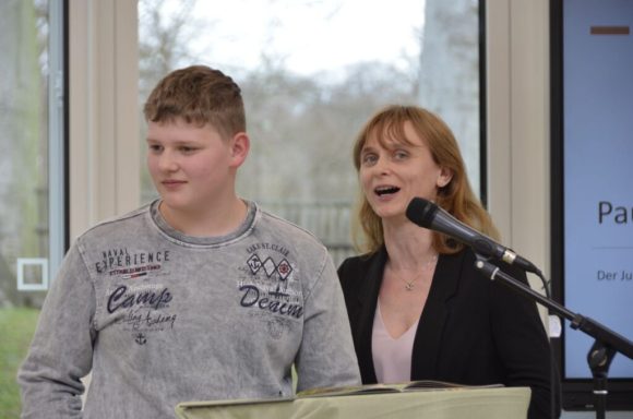 Ein Junge und eine Frau stehen am Mikrofon und sprechen bei einer Veranstaltung.