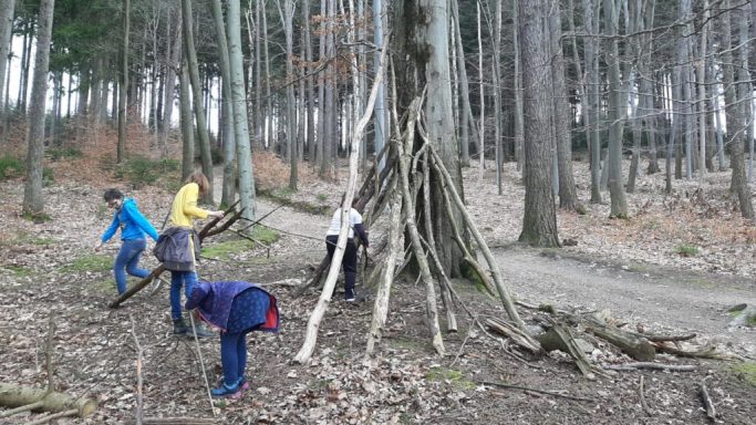 Vier Kinder bauen eine praktische Unterkunft aus Ästen im Wald.