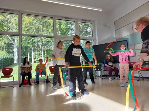 Kinder nehmen an einem Spiel mit bunten Bändern in einem Raum teil.