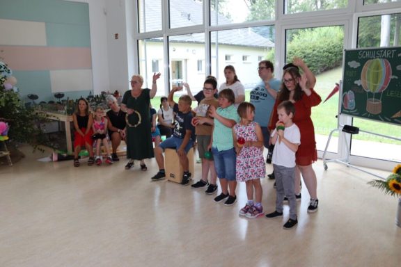 Gruppe von Kindern und Erwachsenen in einem Raum, einige halten Spielzeuge und zeigen Freude.