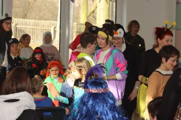 Gruppenszene mit Kindern in Kostümen, feiern zusammen in einem hellen Raum.