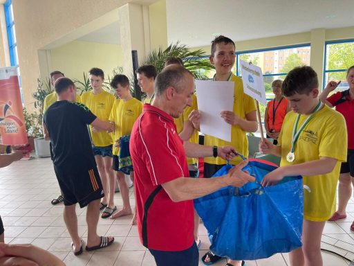 Gruppenszene von Jungen in gelben T-Shirts, die Medaillen und Dokumente erhalten.