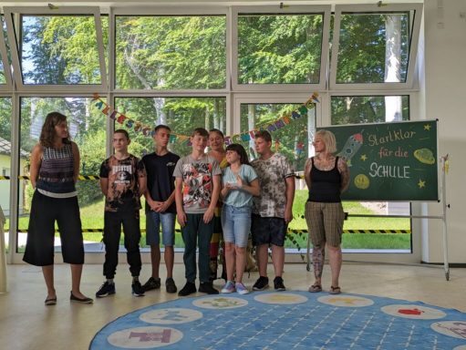 Gruppe von Kindern und Erwachsenen bei einer Veranstaltung in einem hellen Raum.