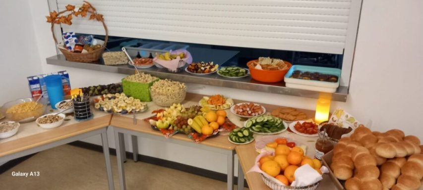 Bunte Buffet-Auslage mit Obst, Gemüse, Brot und Desserts auf den Tischen.