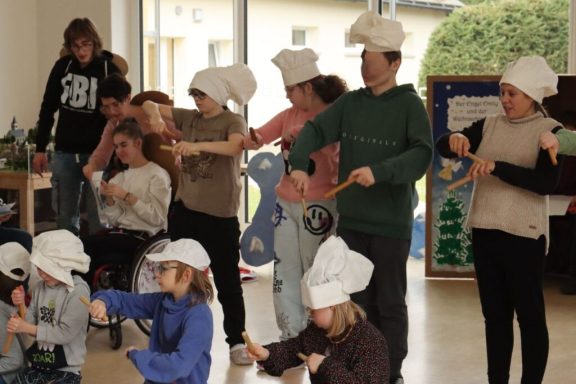 Kinder in Kochmützen führen eine Aufführung in einem Raum durch.