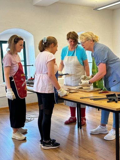 Vier Personen stehen um einen Tisch, arbeiten gemeinsam an einem Projekt.