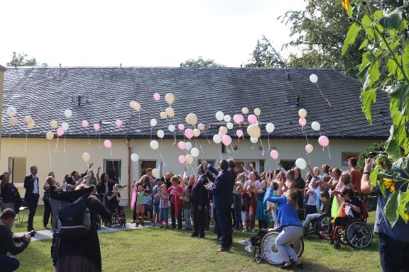 Menschen feiern im Freien, Luftballons steigen in den Himmel.