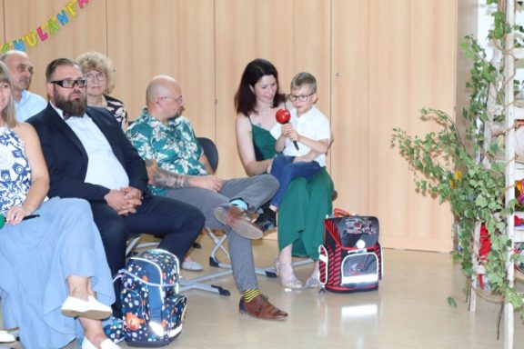 Eine Gruppe von Personen sitzt, eine Frau hält ein Kind im Arm.