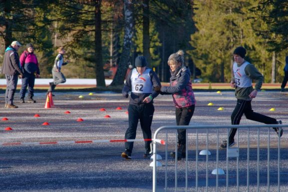 Teilnehmer trainieren im Freien mit farbigen Markierungen und einer Trainerin.