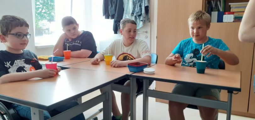 Vier Kinder sitzen an einem Tisch und arbeiten mit bunten Schalen und Zubehören.