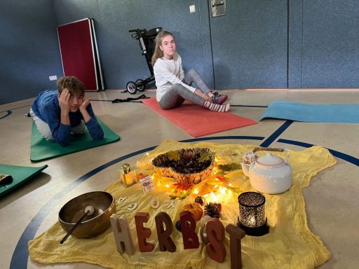 Zwei Personen auf Yogamatten, mit einer dekorierten Mitte aus Kerzen und Früchten.