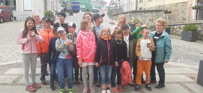 Eine Gruppe von Kindern steht lächelnd auf einer Straße in einer Stadt.