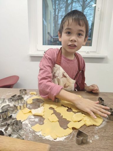 Ein Junge rollt Teig aus und sticht Formen für Plätzchen aus.