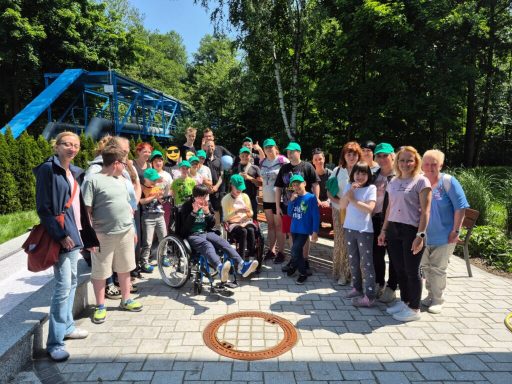 Gruppenfoto von Kindern und Erwachsenen mit grünen Hüten in einem Park.