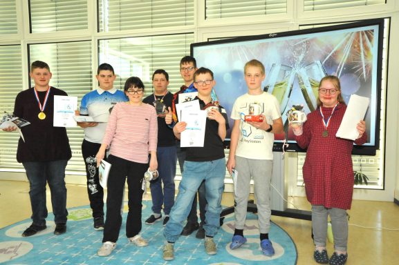 Gruppe von acht Jugendlichen mit Urkunden und Medaillen bei einer Veranstaltung.