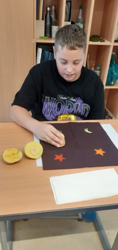 Ein Junge arbeitet an einem Tisch mit Papier und farbigen Formen.