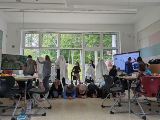 Gruppenszene von Personen in einem Raum, einige knien, andere stehen und feiern.