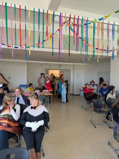 Menschen in einem festlich dekorierten Raum, Versammlung mit bunten Bändern und Kostümen.