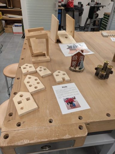 Holztisch mit Bastelmaterialien, darunter kleine Holzformen und Informationskarten.