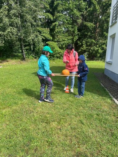 Drei Kinder spielen im Freien mit einem Tisch und einem Kürbis.