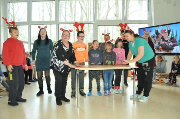 Gruppenzusammenkunft mit weihnachtlichen Kopfbanden und einer Aktivität am Tisch.