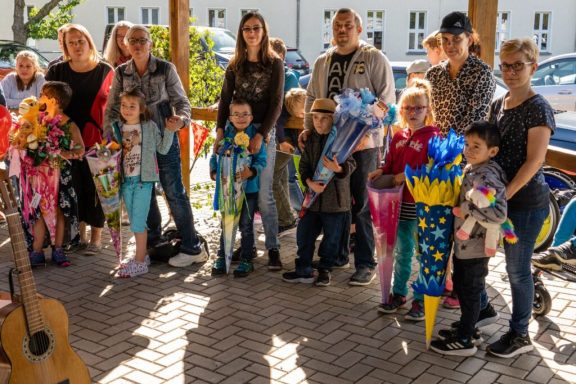 Gruppe von Kindern und Erwachsenen mit bunten Laternen und festlicher Kleidung.