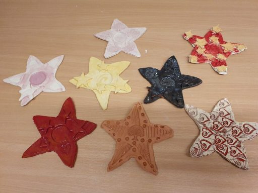 Bunte, sternförmige Bastelobjekte aus Papier in verschiedenen Farben und Mustern.