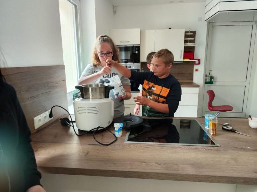 Zwei Kinder bereiten in einer modernen Küche etwas in einer Küchenmaschine zu.