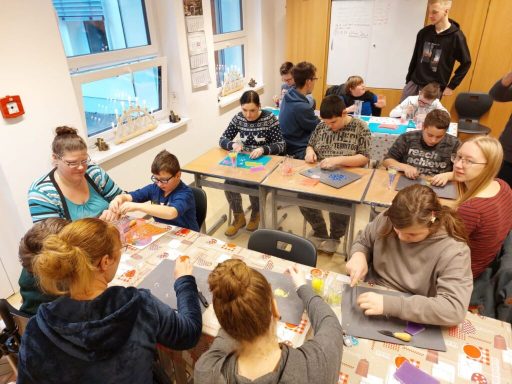 Schüler und Lehrer arbeiten gemeinsam an Bastelprojekten in einem Klassenraum.
