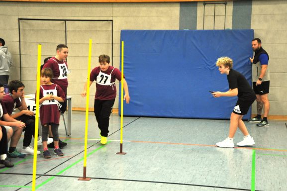 Jugendliche im Wettkampf, springen über Hindernisse in einer Sporthalle.