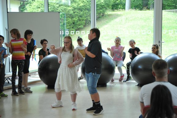 Kinder führen eine kreative Darbietung auf, umgeben von großen Bällen.