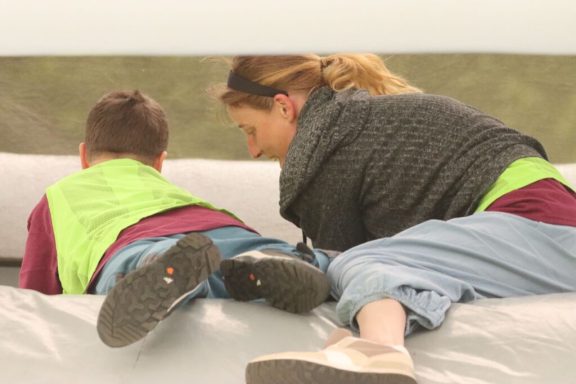 Ein Kind und eine Frau liegen nebeneinander und betrachten etwas im Freien.