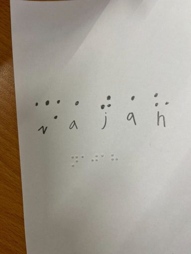 Braille-Schrift zeigt das Wort "wajah" auf weißem Papier.