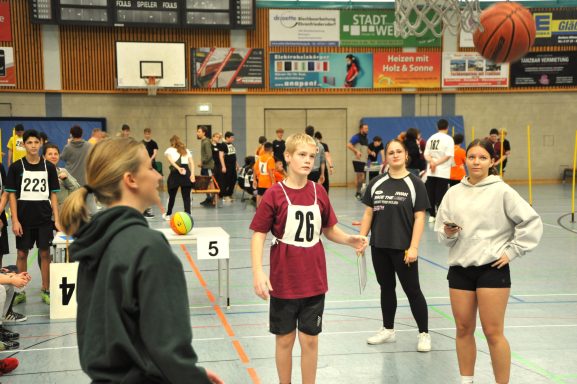Jugendliche in der Halle beim Basketballspielen und Training in sportlicher Kleidung.