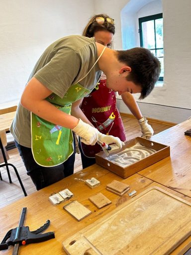 Jugendliche und Erwachsene arbeiten gemeinsam an einem Tisch mit Objekten zur Analyse.