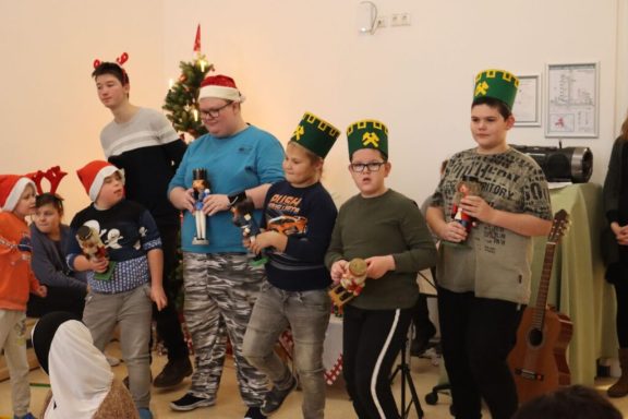 Gruppe von Kindern in Festtagsmützen, die fröhlich mit Instrumenten posieren.